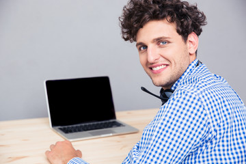 Smiling man sitting at the table with laptop