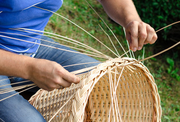 Man's hands making a wicker basket