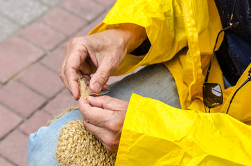 Man's hands making a straw sandals