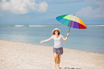 Cheerful young girl with rainbow umbrella having fun on the