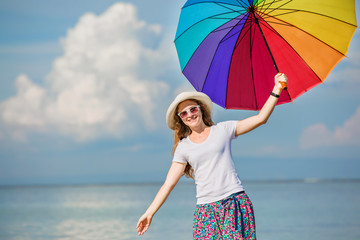 Cheerful young girl with rainbow umbrella having fun on the