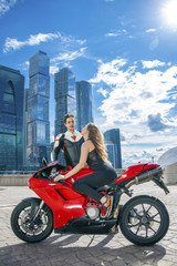 Fototapeta na wymiar Young couple on a sports bike on the background of the city skyl