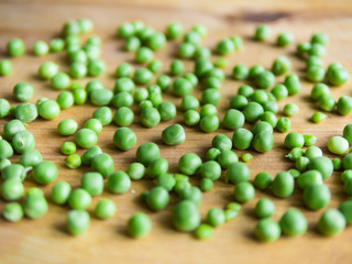 Scattered podded peas on a wooden board