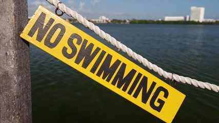No swimming sign on wooden tablet near lagoon
