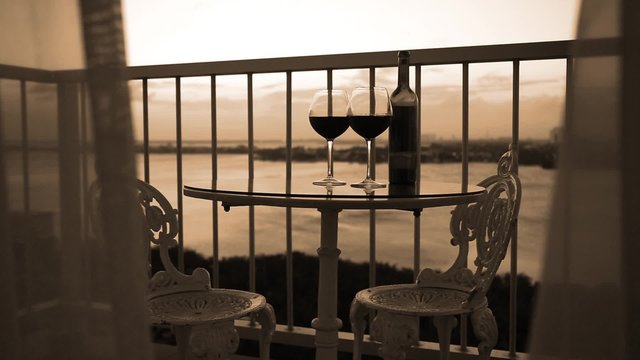 Romantic evening with red wine on balcony overlooking at sunset
