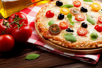 Italian pizza with cheese, tomatoes, olives and basil