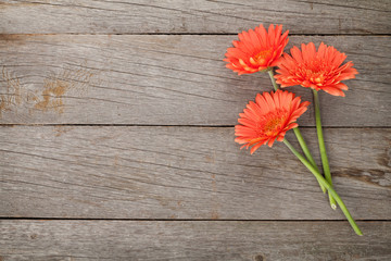 Houten ondergrond met oranje gerbera bloemen