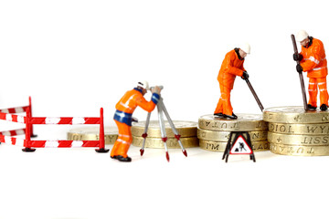 Miniature construction workers pound coins.
Miniature scale model construction workers with British pound coins.  Growing money concept. - Powered by Adobe