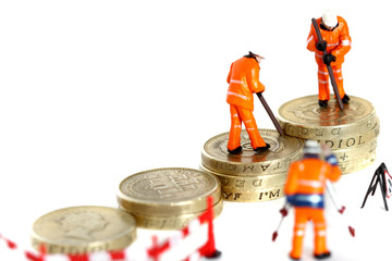 Miniature construction workers pound coins.
Miniature scale model construction workers with British pound coins.  Growing money concept.