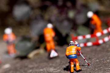 Fototapeta premium Miniature construction workers weeding. Miniature scale model construction workers weeding garden path.
