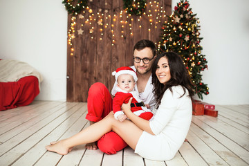 Hipster father and mother holding baby in santa suit