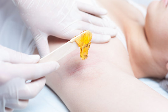 Professional woman at spa doing epilation armpits using sugar - sugaring