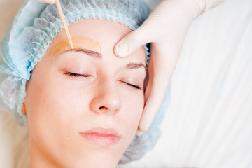 Obraz na płótnie Canvas Beautiful woman in spa salon receiving epilation or correction eyebrow
