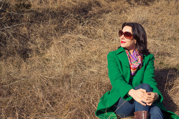 Woman sitting on the hay in a green coat