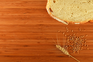 Cutting board with wheat ear, grains and slice of bread