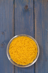 dry pasta in bowl on blue background