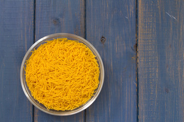 dry pasta in bowl on blue wooden background