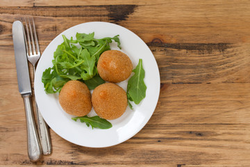 meat croquette on white plate on brown wooden background