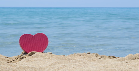 Fototapeta premium Heart shape dipped in sandy beach with the look at horizon