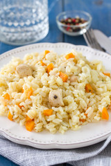 rice with meat and carrot on white plate and glass of water