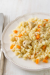 rice with meat and carrot on white plate on white wooden background