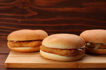 Chicken burgers on bamboo board on wooden table