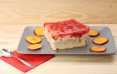 Strawberry and peach cake with gelatin on grey plate on wooden t