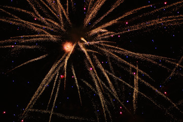 Fireworks exploding in the night sky leaving several trails