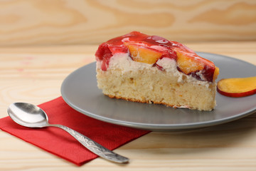 Strawberry and peach cake with gelatin on grey plate on wooden t