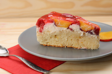 Strawberry and peach cake with gelatin on grey plate on wooden t