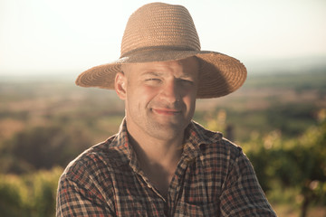Portrait of male vintner with hat posing at vineyard