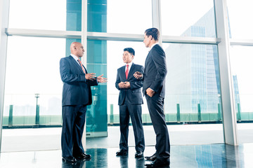 Three businesspeople standing in office lobby