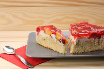 Strawberry and peach cake with gelatin on grey plate on wooden t