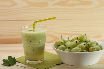 Smoothie from gooseberries in a glass and gooseberries in bowl
