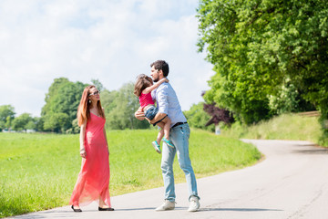 Mama, Papa und Kind machen Spaziergang auf einem Wiesenweg