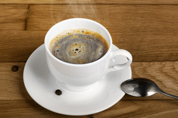 Hot fresh coffee in a white cup with spoon