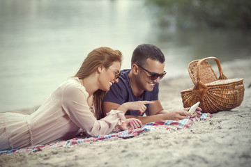 Young couple relaxing on the beach and using digital tablet