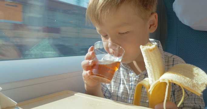 Little boy eats while travelling by train 