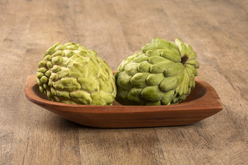 Obraz premium Some Sugar-Apples over a wooden table. Atemóia