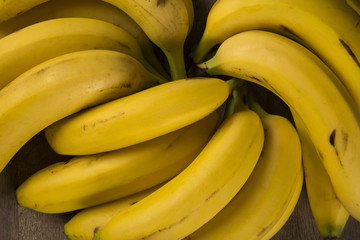 A banch of bananas and a sliced banana in a pot over a table.