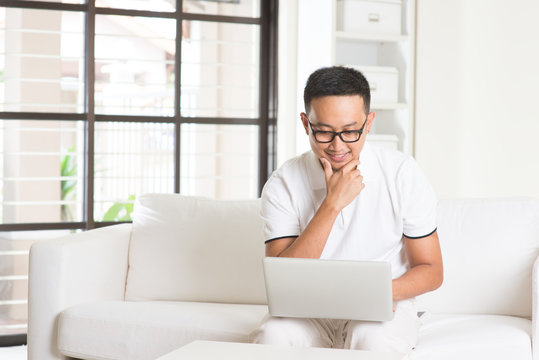 Southeast Asian Male Using Internet At Home, Sitting On Sofa Rel