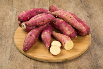 Raw sweet potatoes on wooden background closeup