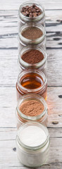 Coffee beans, coffee powder, creamer, cocoa powder, honey and processed tea leaves in a mason jar over weathered wooden background