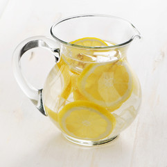 Water with lemon in glass jug.