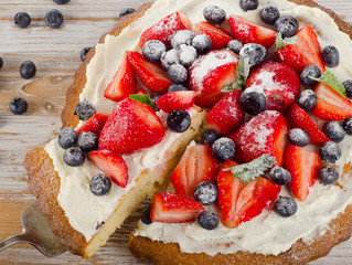 Cake with fresh berries on   a wooden background.