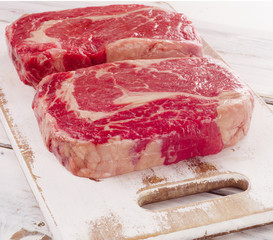 Raw fresh Ribeye Steak on a wooden cutting board