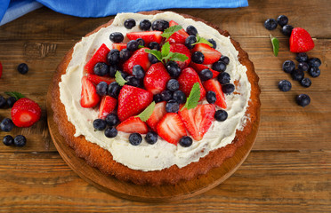 Strawberry and blueberry  cream cake on  rustic wooden backgroun