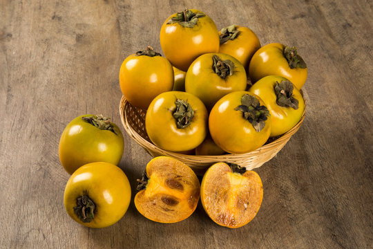 Some khaki fruits over a wooden surface
