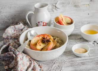 oatmeal with caramelized apples and cinnamon in a white bowl on a light wooden background