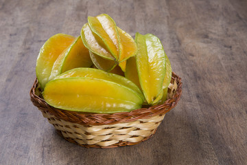 Some caramboles in a basket over a wooden surface